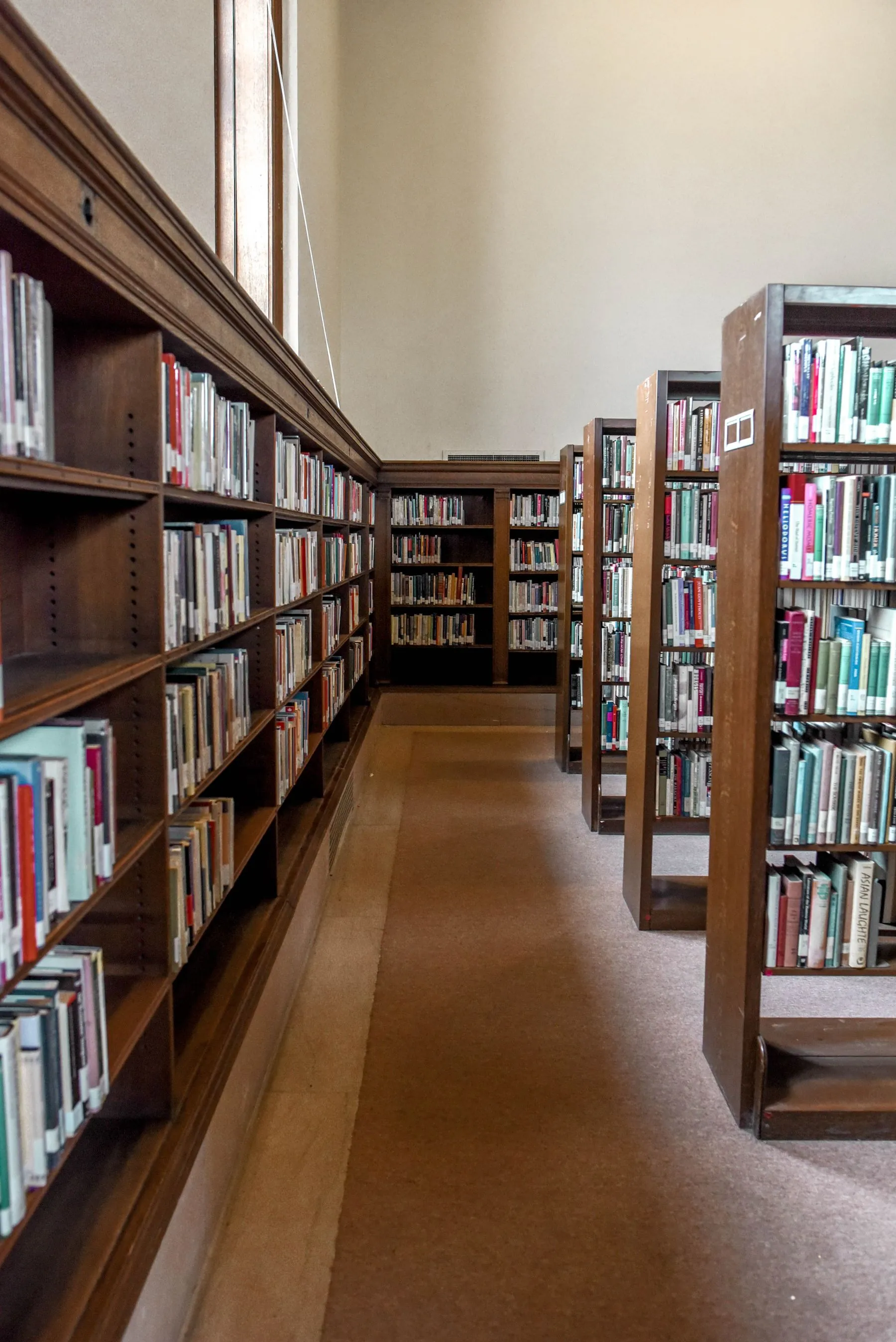 An empty aisle lined with wooden bookshelves