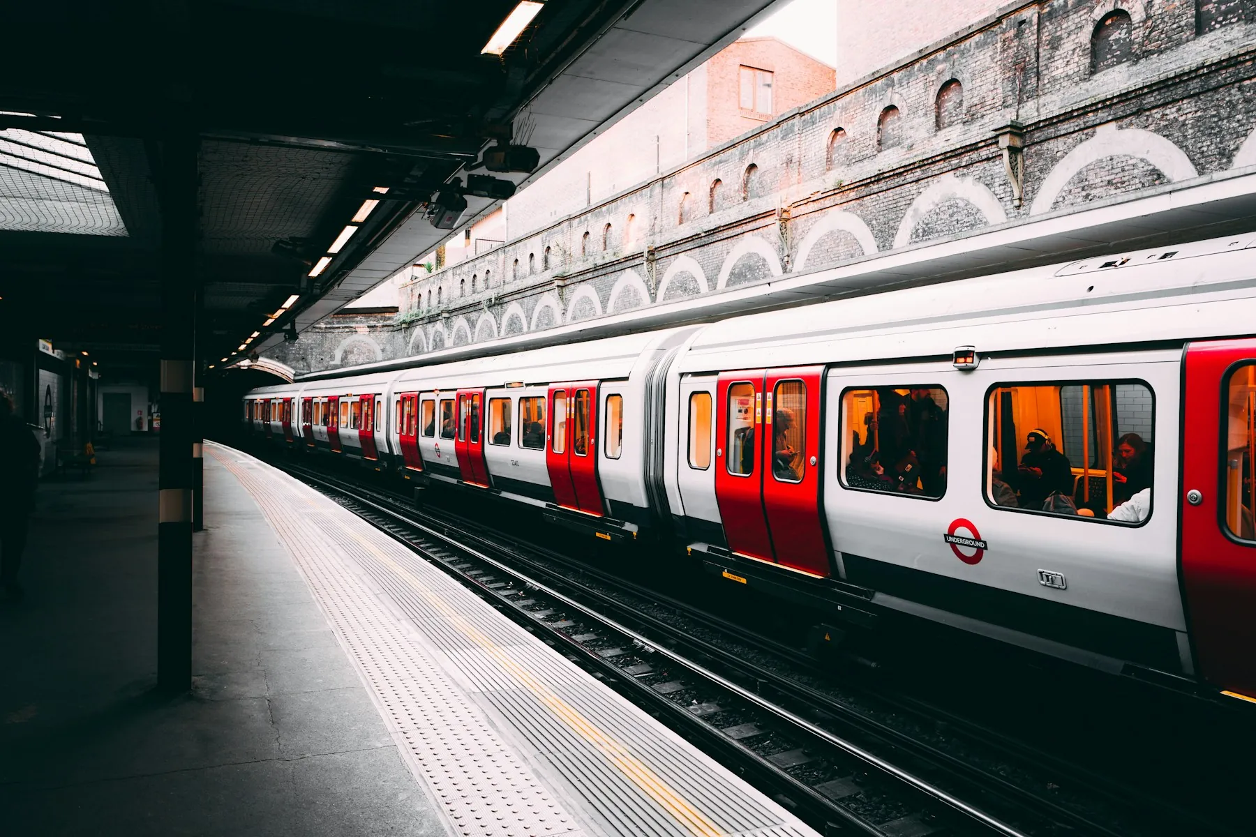 A red and white train passing an urban station