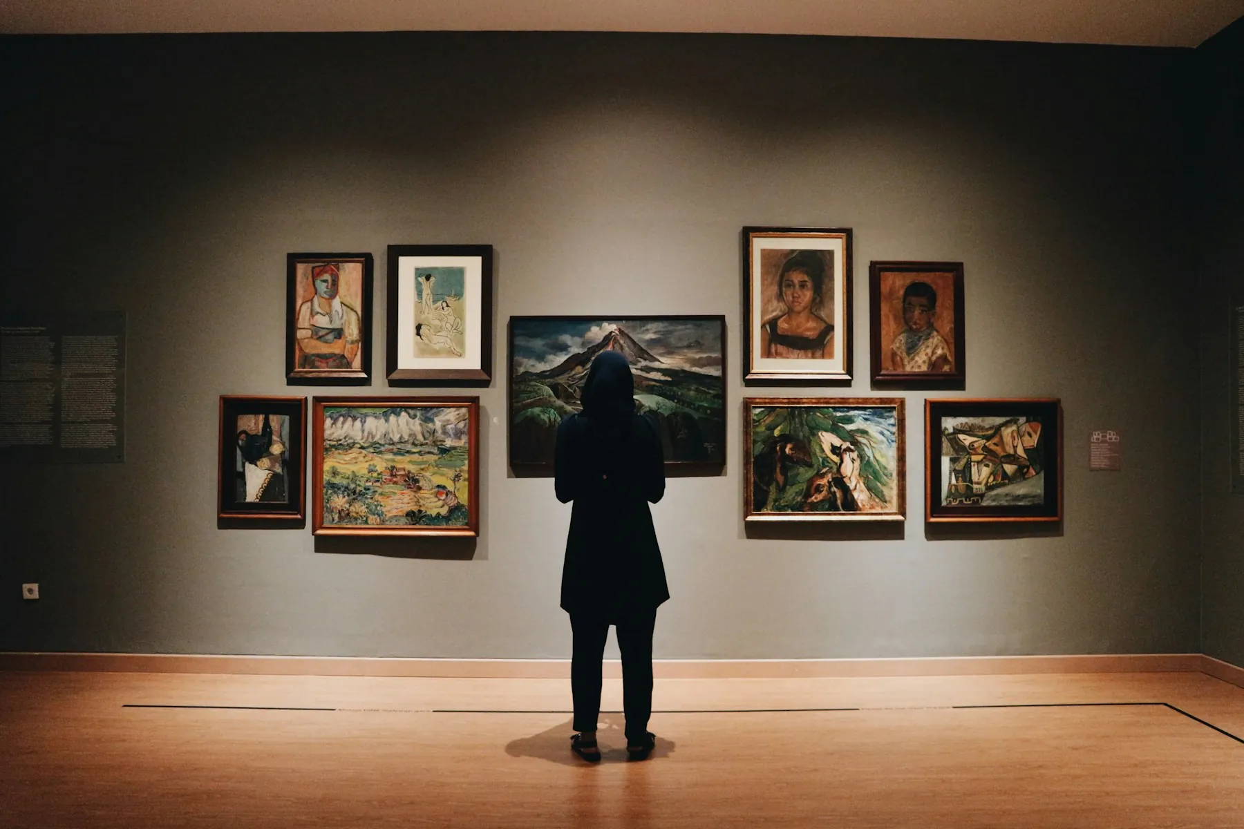 A visitor looking at framed paintings in a museum